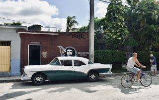 Classic car parked outside building with Che Guevara image in Santa Clara Cuba